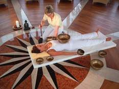 Eine Frau bekommt eine entspannende Klangschalenmassage in einem lichtdurchfluteten Raum im Hotel Mooshof.