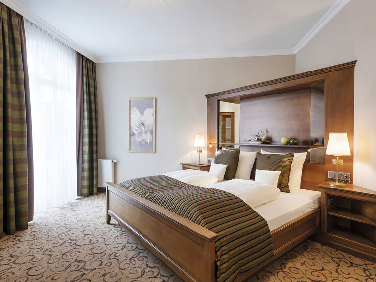 Sanftes Licht fällt auf das luxuriöse Kingsize-Bett in der Wellnesssuite Bergzauber im 4-Sterne-Spa-Hotel Mooshof im Bayerischen Wald.