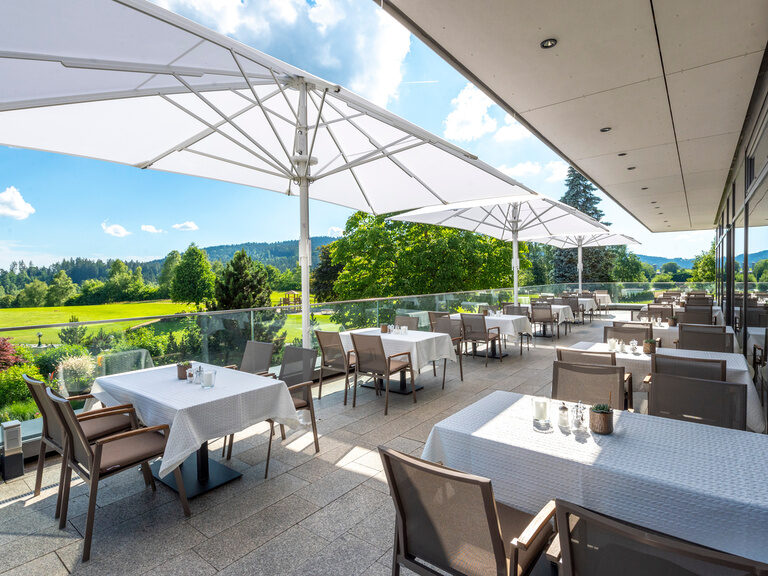 Das Restaurant des Wellnesshotels Mooshof im Bayerischen Wald mit Außenbestuhlung und Sonnenüberdachung auf der Panoramaterrasse.