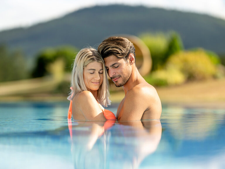 Ein verliebtes Paar genießt die Sonne im Aussenpool des Wellnesshotels Mooshof im Bayerischen Wald.