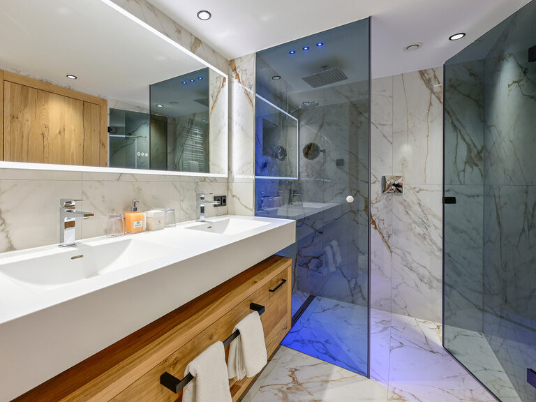 Modernes Badezimmer mit großem Spiegel und Dusche im Zimmer Typ 3A des Wellnesshotels Mooshof im Bayerischen Wald.