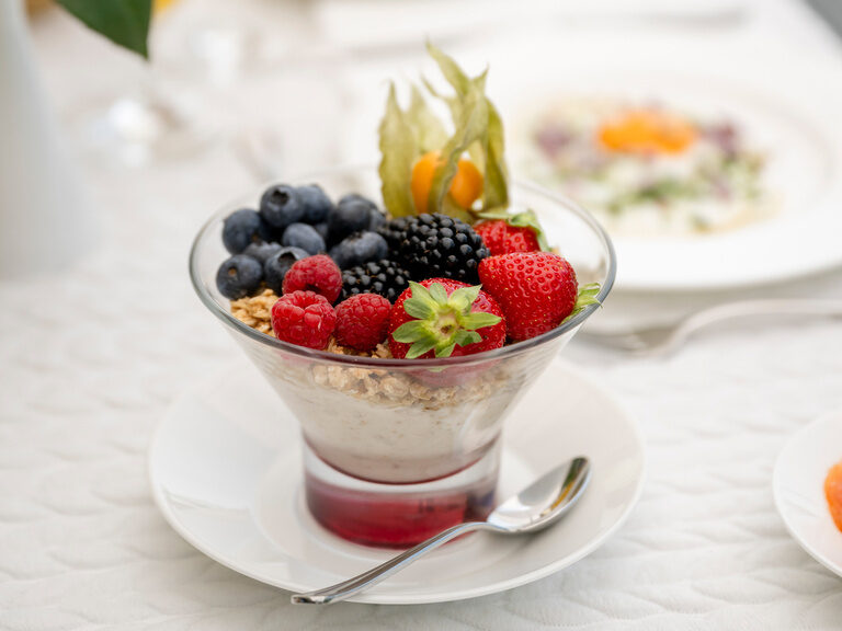 Eine leckere Schale mit frischem Obst und Beeren auf einem Frühstückstisch im Hotel Mooshof in Bayern.