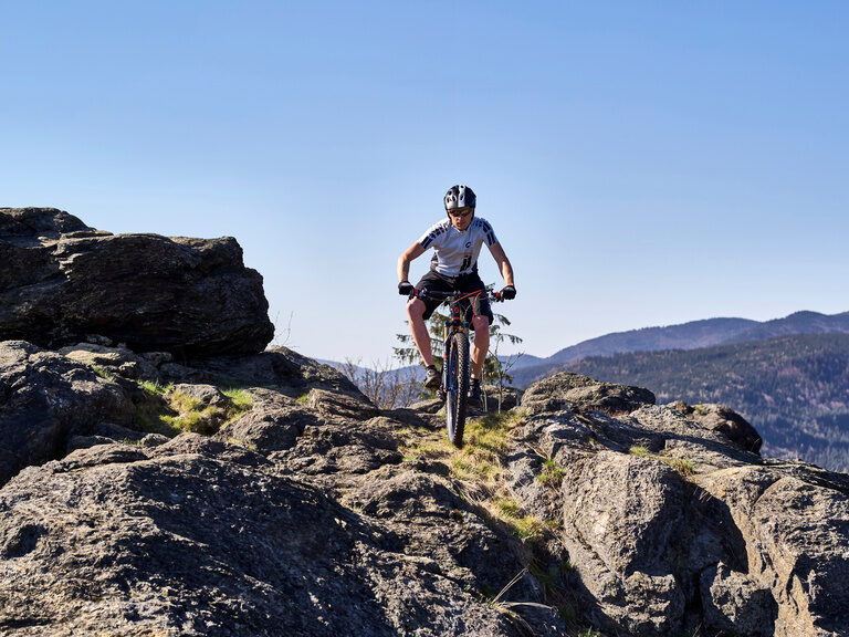 Ein Mann fährt mit einem Mountainbike auf einem felsigen Pfad in der Nähe des Großen Arbers.