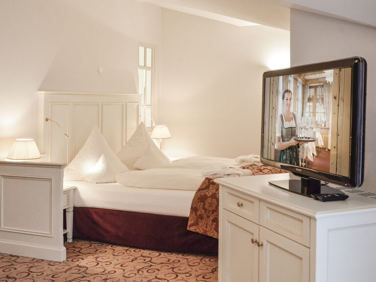 Einladendes Bett mit Fernseher in der Berkhain Suite Deluxe des Wellnesshotels Mooshof im Bayerischen Wald, perfekt für erholsame Nächte.
