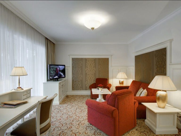 Elegant eingerichtetes Wohnzimmer in der Birkenhain-Suite des Wellnesshotels Mooshof in Bodenmais mit Samtmöbeln und großem Flachbildfernseher.