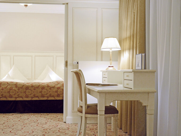 Stilvoller Schreibtisch mit passendem Stuhl vor dem gemütlichem Bett in der Birkenhain-Suite des Wellnesshotels Mooshof im Bayerischen Wald.