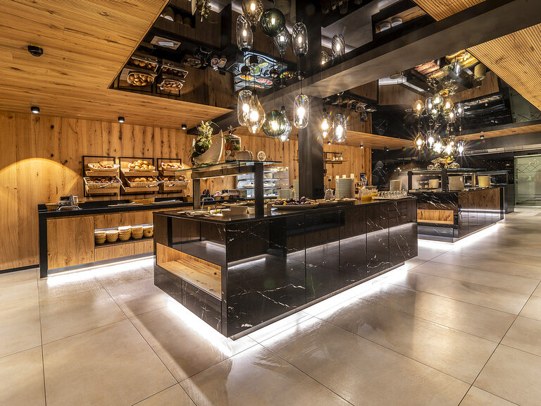 Der beleuchtete moderne Buffetbereich im Restaurant des Wellnesshotels Mooshof im Bayerischen Wald mit einer vielfältigen Auswahl von leckeren Speisen.