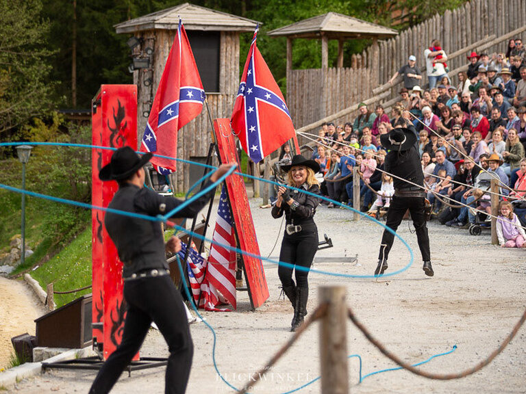 Eine Gruppe von Menschen in Coboy Kostümen schwingt ihre Lassos auf einem öffentlichen Festival in Pullman City.