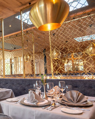 Schickes Restaurant mit edler Beleuchtung und einladend gedeckten Tischen im Wellnesshotel Mooshof im Bayerischen Wald.