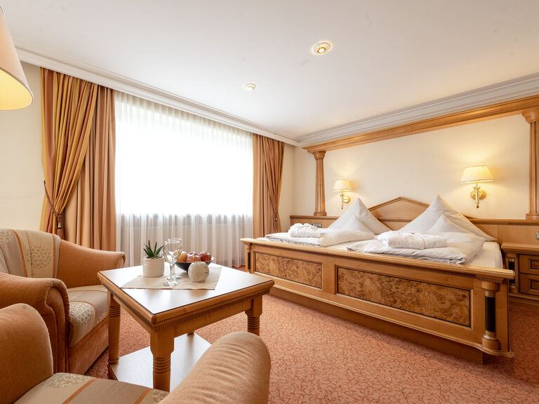 Die Einrichtung des Zimmers Typ 11 des Hotels Mooshof in Bayern umfasst ein großes Bett und zwei Sessel zum Entspannen.