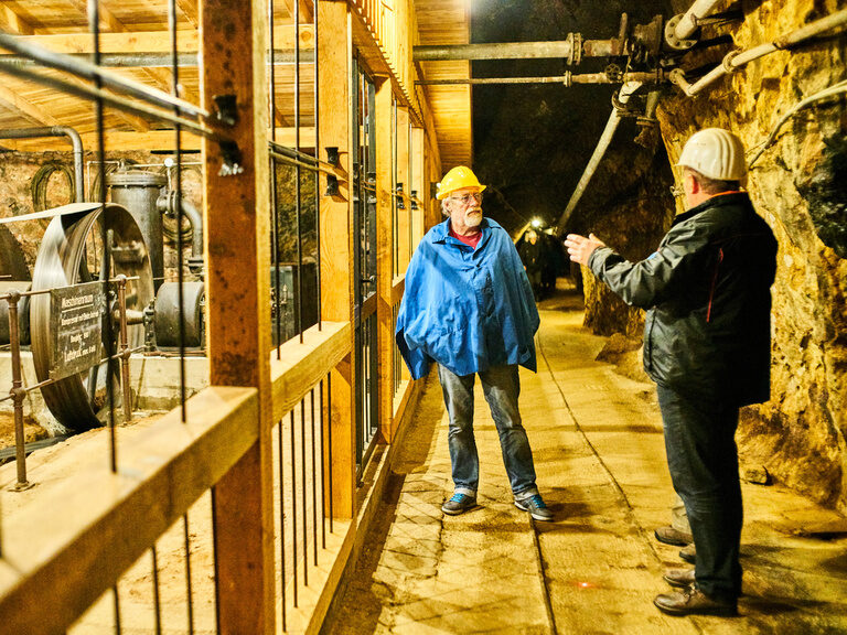 Zwei Bergleute stehen am Eingang eines mystischen Bergwerks.