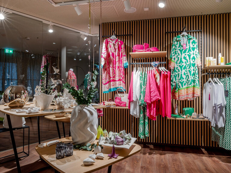 Moderner Shop mit dekorativ präsentierten Kleidungsstücken auf den Regalen im Wellnesshotel Mooshof in Bodenmais.