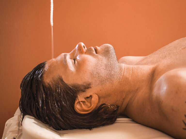 In einem Wellness-Raum des Hotels Mooshof in Bodenmais ruht ein Mann entspannt mit geschlossenen Augen auf einem Massagetisch.