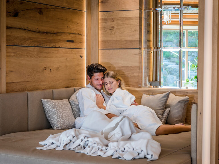 Ein Paar sitzt entspannt auf einem Kuschelnest in einem Ruheraum des Wellnessbereiches vom Hotel Mooshof im Bayerischen Wald.