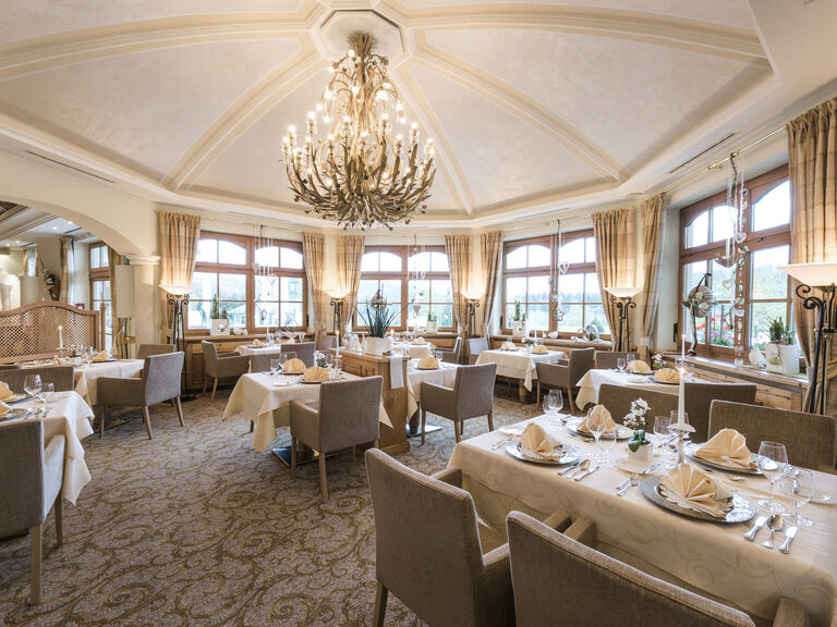Der große Speisesaal im Wellnesshotel Mooshof Restaurant Erkerlounge mit vielen Tischen und Stühlen, ideal für Dinner.