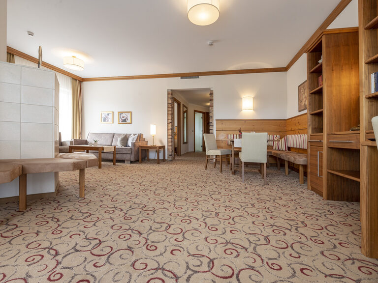 Einladender offener Wohnraum mit gemütlicher Couch und Sitzecke in der Erkersuite Deluxe des Wellnesshotels Mooshof im Bayerischen Wald.