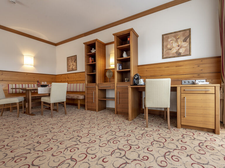 Gemütlicher Sitzbereich mit Eckbank und praktischem Schreibtisch in der Erkersuite Deluxe des Wellnesshotels Mooshof im Bayerischen Wald.