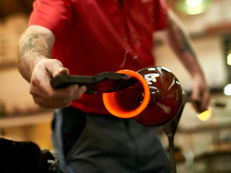 Ein Mann macht letzte Feinschliffe an einem Kunstwerk aus Glas.