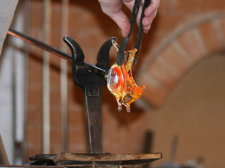 Ein Arbeiter fertig aus Glas einen filigranen Vogel.