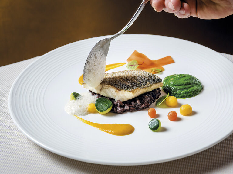 Ein elegant angerichteter Fisch auf Gemüse im Wellness & SPA Resort Mooshof im Bayerischen Wald..