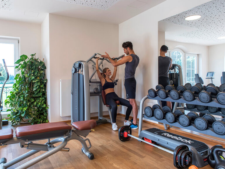 Eine Frau nutzt die modernen Fitnessgeräte beim Krafttraining im Hotel Mooshof in Bodenmais.