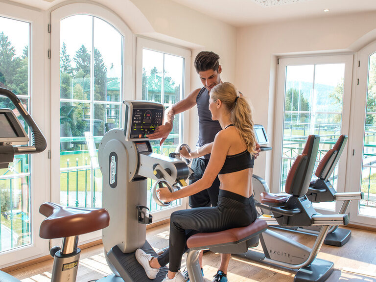 Im großzügigen Fitnessstudio des Hotels Mooshof in Bodenmais treibt ein Paar auf Fitnessgeräten Sport.