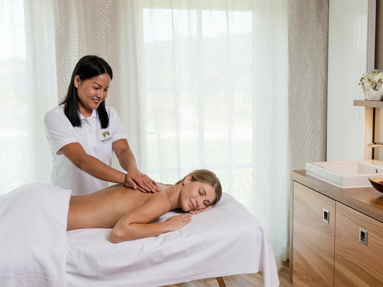 Entspannung pur bei einer Massage auf einem gemütlichen Massagetisch des Wellnesshotels Mooshof im Bayerischen Wald.
