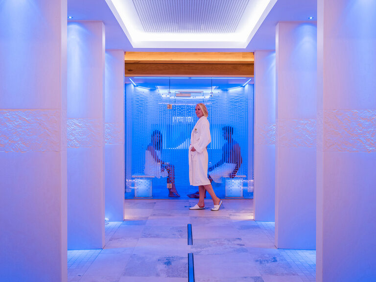 Eine Frau vor der modernen Sauna im Wellnessresort Mooshof.