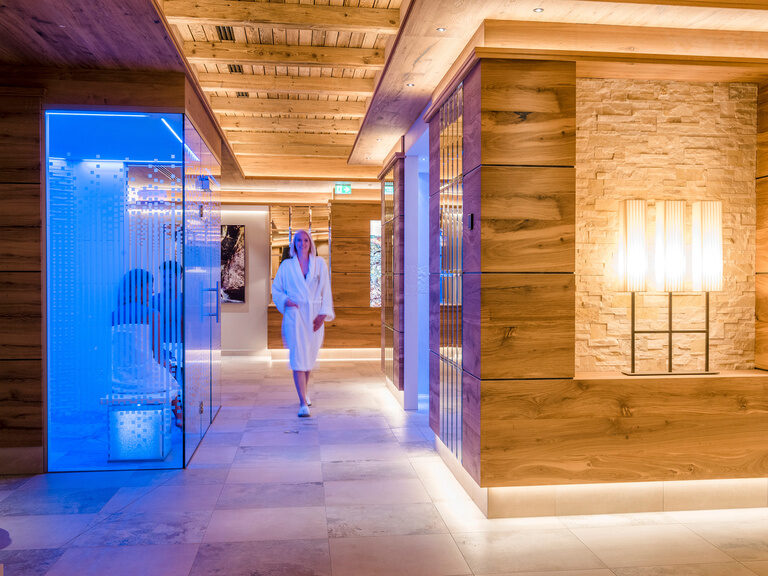 Eine Frau im Bademantel geht an Saunen vorbei.