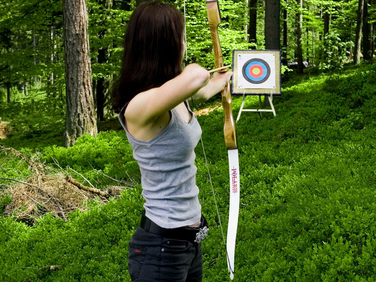 Eine Frau übt zielsicher das Bogenschießer auf eine Zielscheibe im Bayerischen Wald
