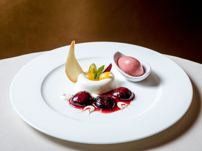 Ein weißer Teller mit verlockendem fruchtigem Dessert in der Welt der kulinarischen Kunst des Restaurants Mooshof im Bayerischen Wald.