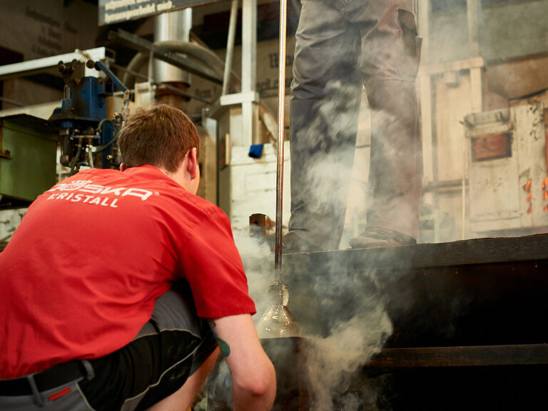 Ein Mann bläst ein Kunstwerk aus heißem Glas.