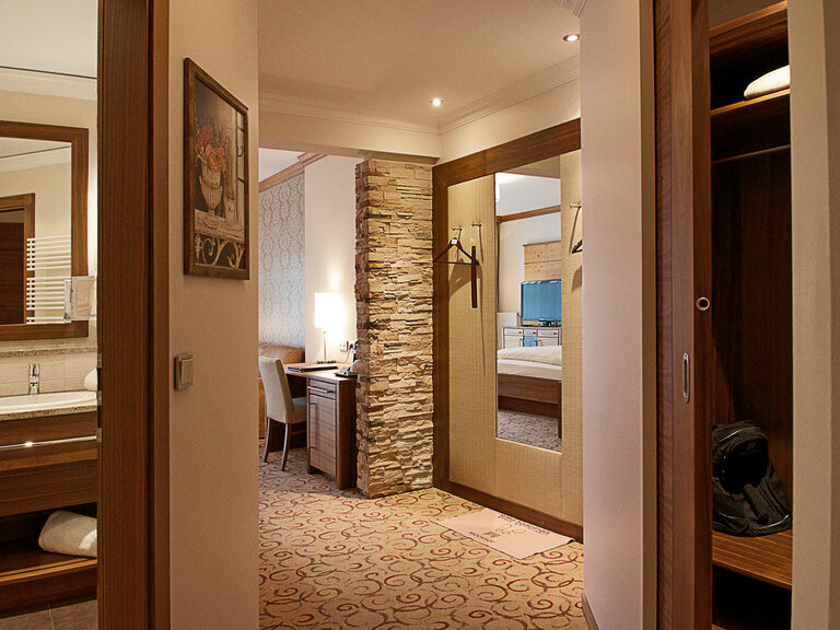 Einladende Einrichtung der Gartensuite des Wellnesshotels Mooshof in Bayern mit modernen Badezimmer und geräumigen Kleiderschrank.