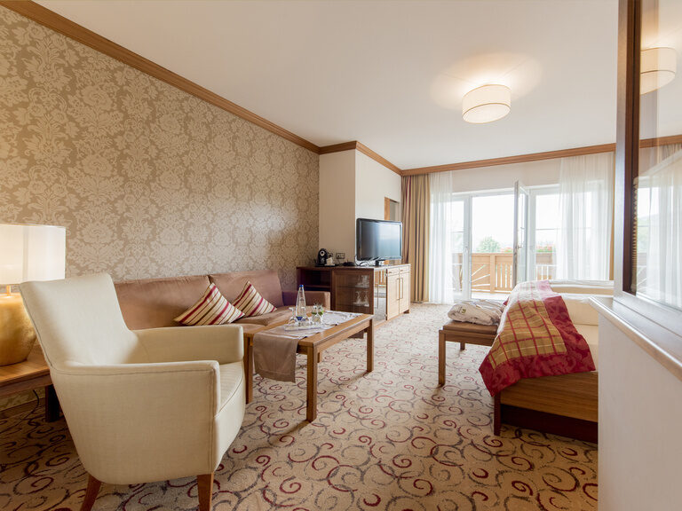 Geschmackvoll eingerichteter Wohnraum in der Gartensuite Schwalbennest des Wellnesshotels Mooshof im Bayerischen Wald mit gemütlichen Sitzgelegenheiten und modernem Fernseher.