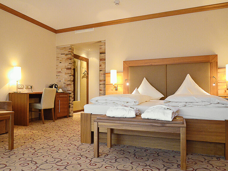 Geschmackvoll gestaltetes Schlafzimmer mit bequemen Bett in der Garten Suite des Wellnesshotels Mooshof in Bodenmais, ideal für Entspannung und Komfort.