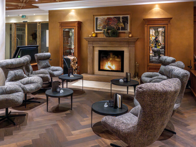Charmante Lounge mit einem einladenden knisternden Kamin und gemütlichen Sesseln im Hotel Mooshof in Bodenmais.