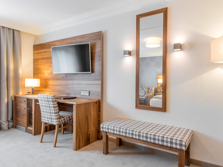Ein einladendes Hotelzimmer mit einem Flachbildfernseher über einem Holzschreibtisch.