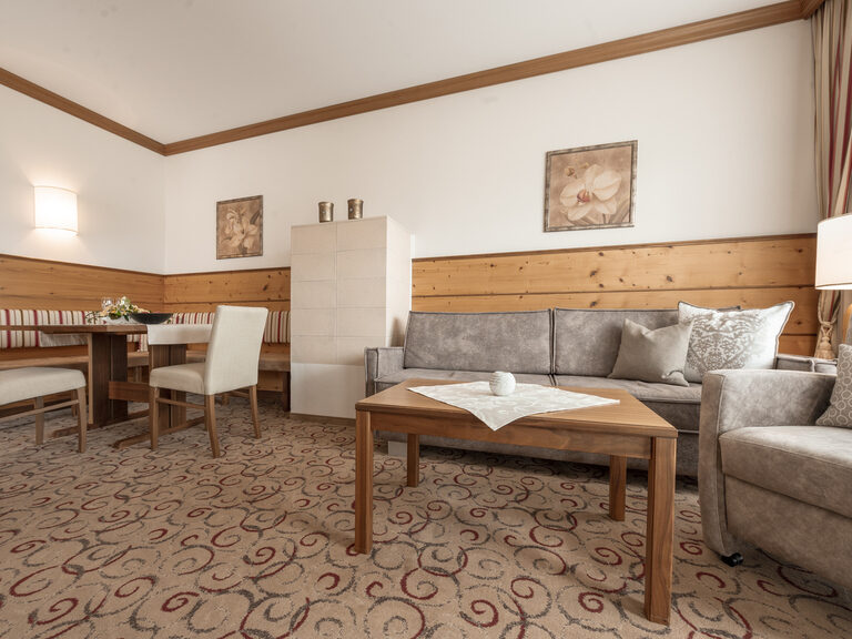Der gemütliche Wohnbereich der Erker Suite des Wellnesshotels Mooshof in Bayern mit Ecksitzbank und Sofa.