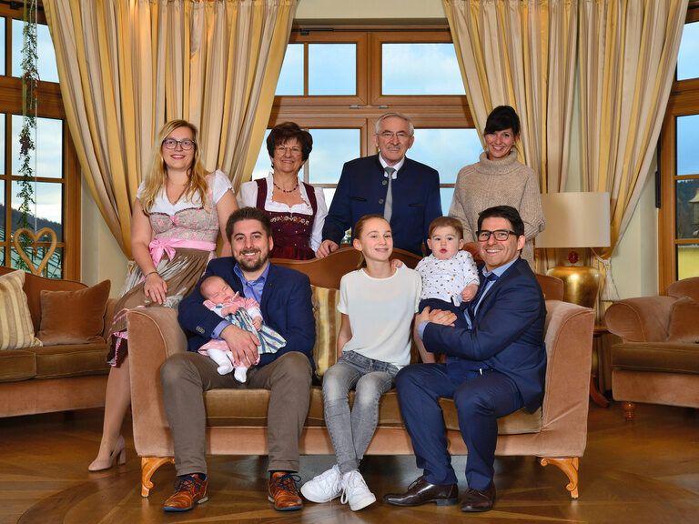 Inniges Familienbeisammensein der Gastgeber bei einem Familienfoto in einer Lounge des Wellnesshotels Mooshof im Bayerischen Wald.