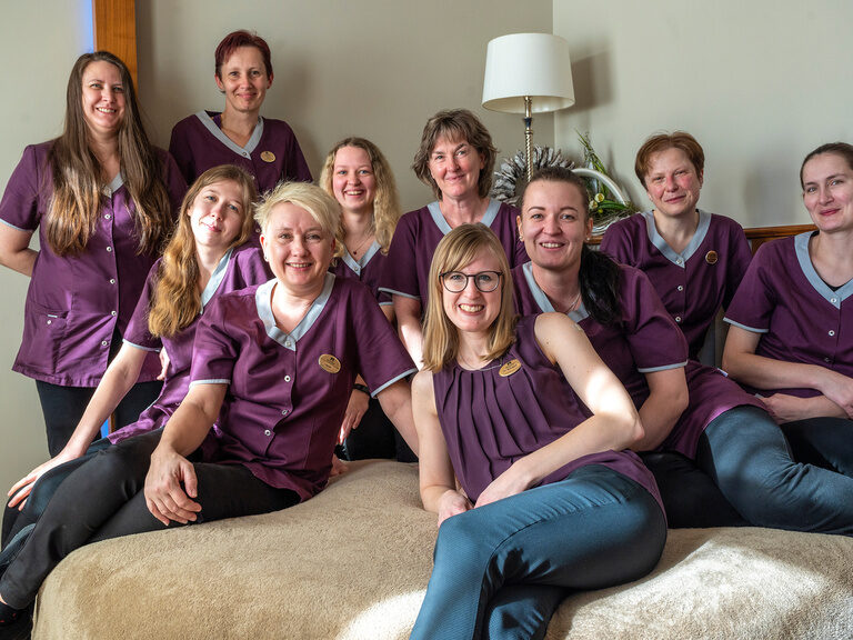 Die fröhliche Zimmermädchen Gruppe genießt den Moment des Zusammenseins auf einem bequemen Bett in einem Zimmer des Wellnesshotels Mooshof im Bayerischen Wald.