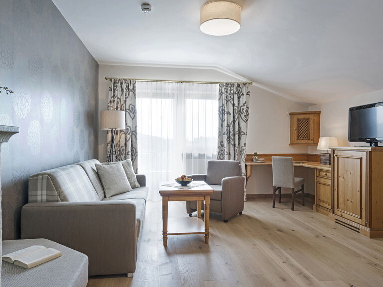 Das geschmackvoll eingerichtete Wohnzimmer in der Harlachbergsuite des Hotels Mooshof in Bodenmais mit Flachbildfernseher und bequemen Sitzgelegenheiten.