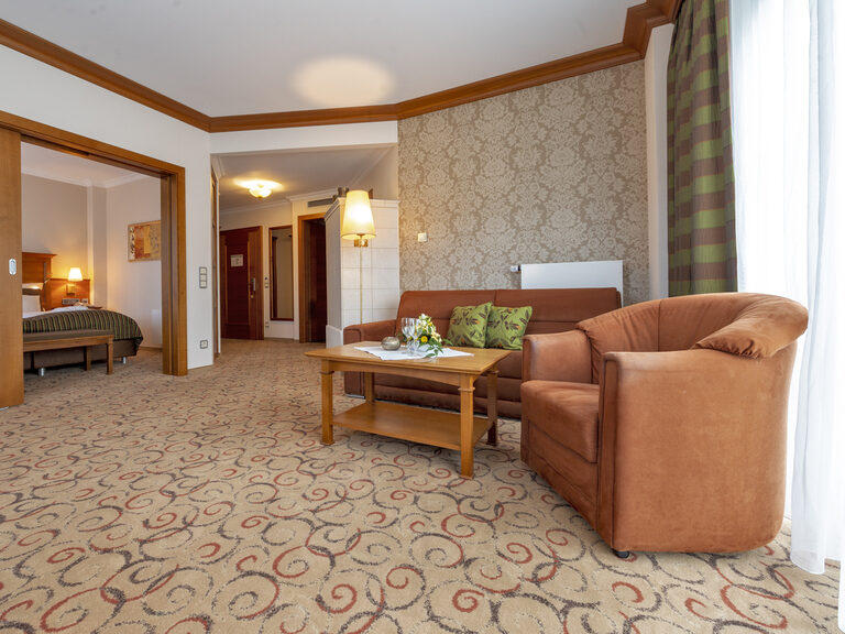 Stilvoll gestalteter Wohnbereich in der Turmsuite Hochzell des Wellnesshotels Mooshof mit einem einladenden Sofa und gemütlichen Sesseln.