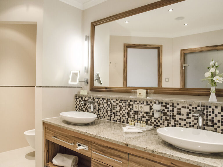 Das edle Badezimmer der Honeymoonsuite des Wellnesshotels Mooshof in Bayern besticht mit Doppelwaschbecken und eleganter Gestaltung.