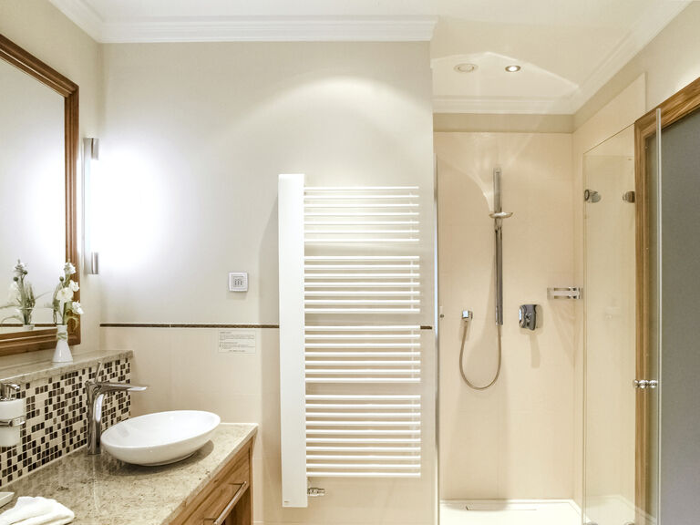 Hell beleuchtetes moderne Badezimmer mit offener Glasdusche und Doppelwaschbecken in der Honeymoonsuite des Wellnesshotels Mooshof in Bodenmais.