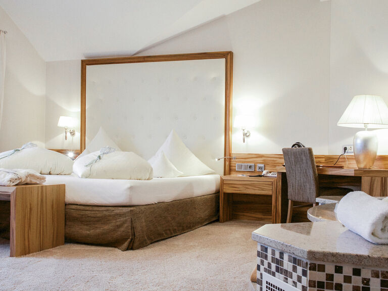 Gemütlicher Schlafbereich in der Honeymoon Suite des Wellnesshotels Mooshof in Bayern mit komfortablen Bett und einem funktionalen Schreibtisch.
