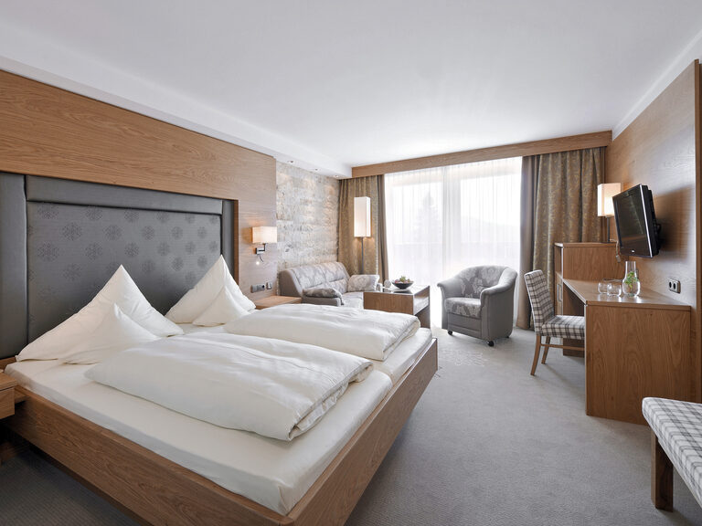 Einladendes Zimmer Typ 9 mit einem modernen Fernseher und Sitzgelegenheit im Wellnesshotel Mooshof in Bodenmais.
