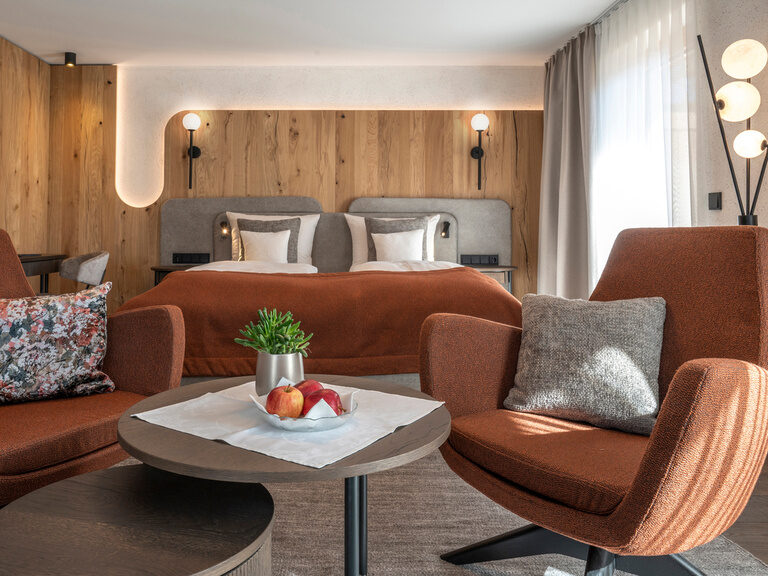 Einladendes Zimmer Typ 3 mit großem Bett und geschmackvollen Sesseln und Couchtisch im Wellnesshotel Mooshof in Bayern.
