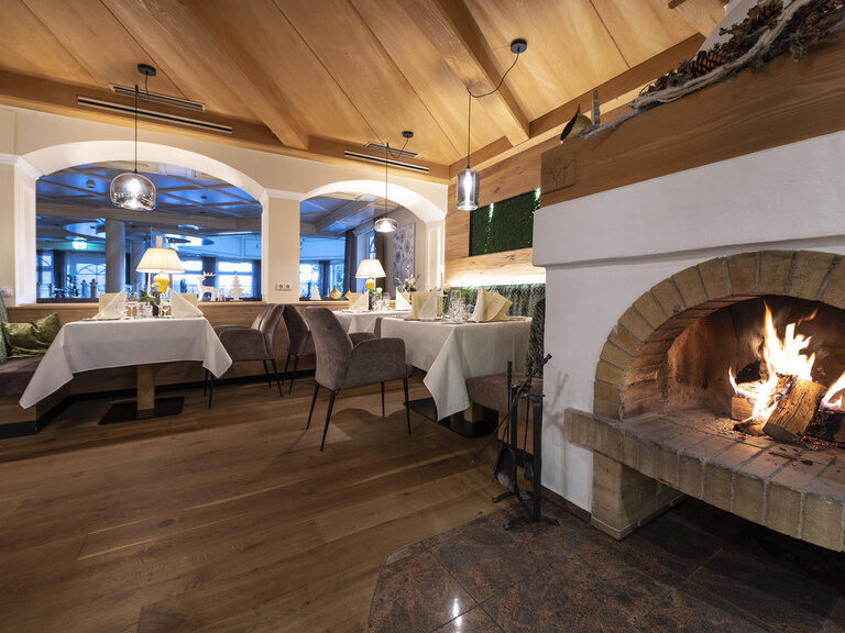 Der moderne Essbereich der Kaminstube des Wellnesshotels Mooshof mit gemütlichem Kamin.