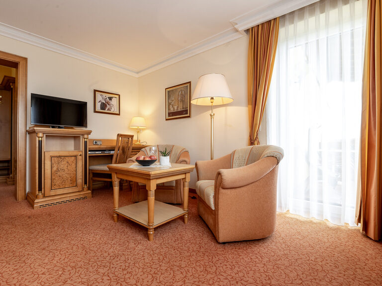 Die harmonisch gestaltete Wohnfläche im Zimmer Typ 11 des Wellnesshotels Mooshof in Bodenmais bietet gemütliche Sitzgelegenheiten und Entertainment.