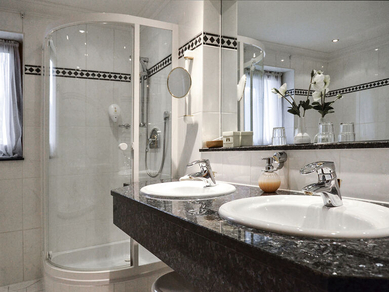 Das moderne Badezimmer in der Classic Juniorsuite des Wellnesshotels Mooshof im Bayerischen Wald mit zwei Waschbecken und großer Dusche.